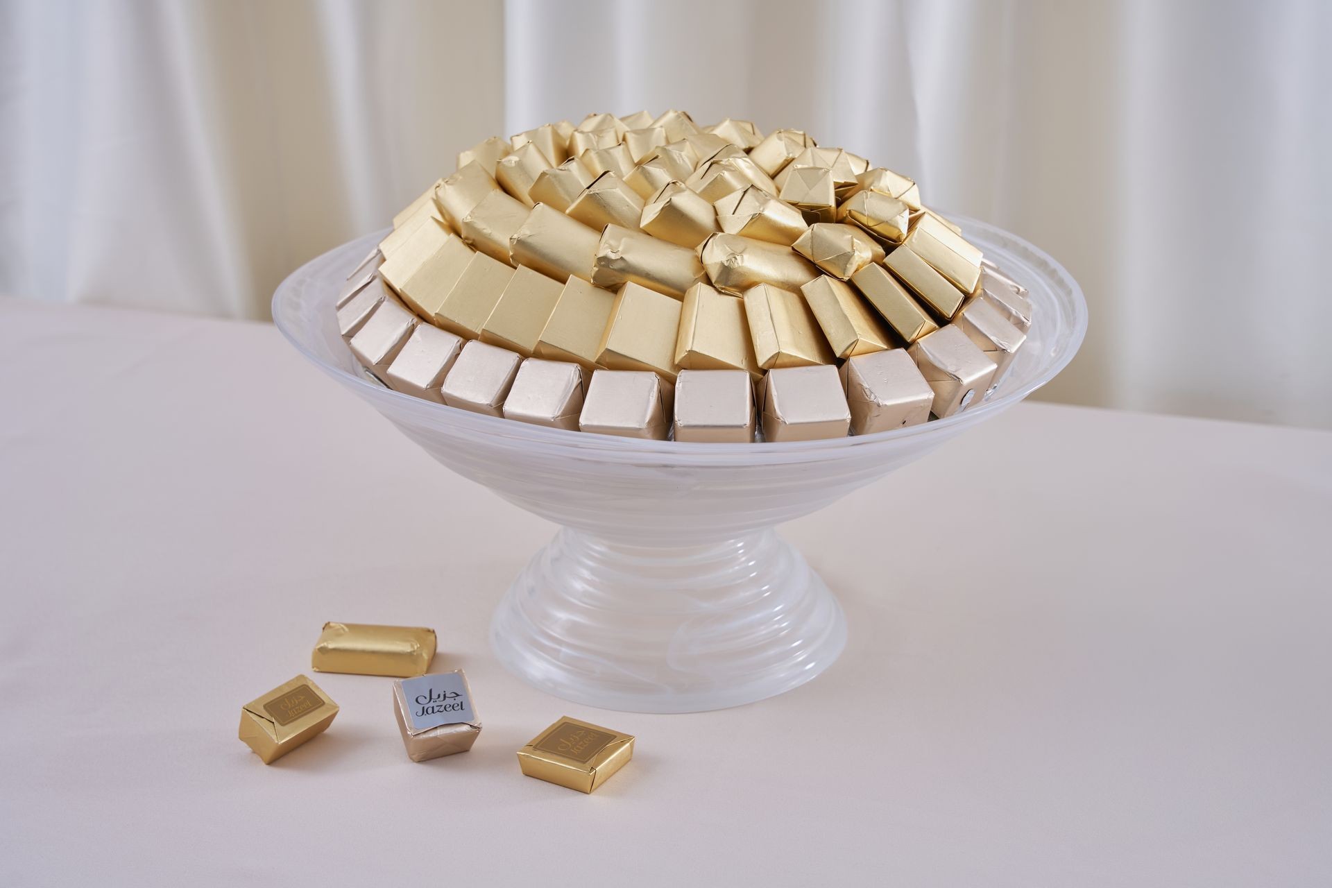 White platter filled with gold and silver wrapped chocolates on a table.
